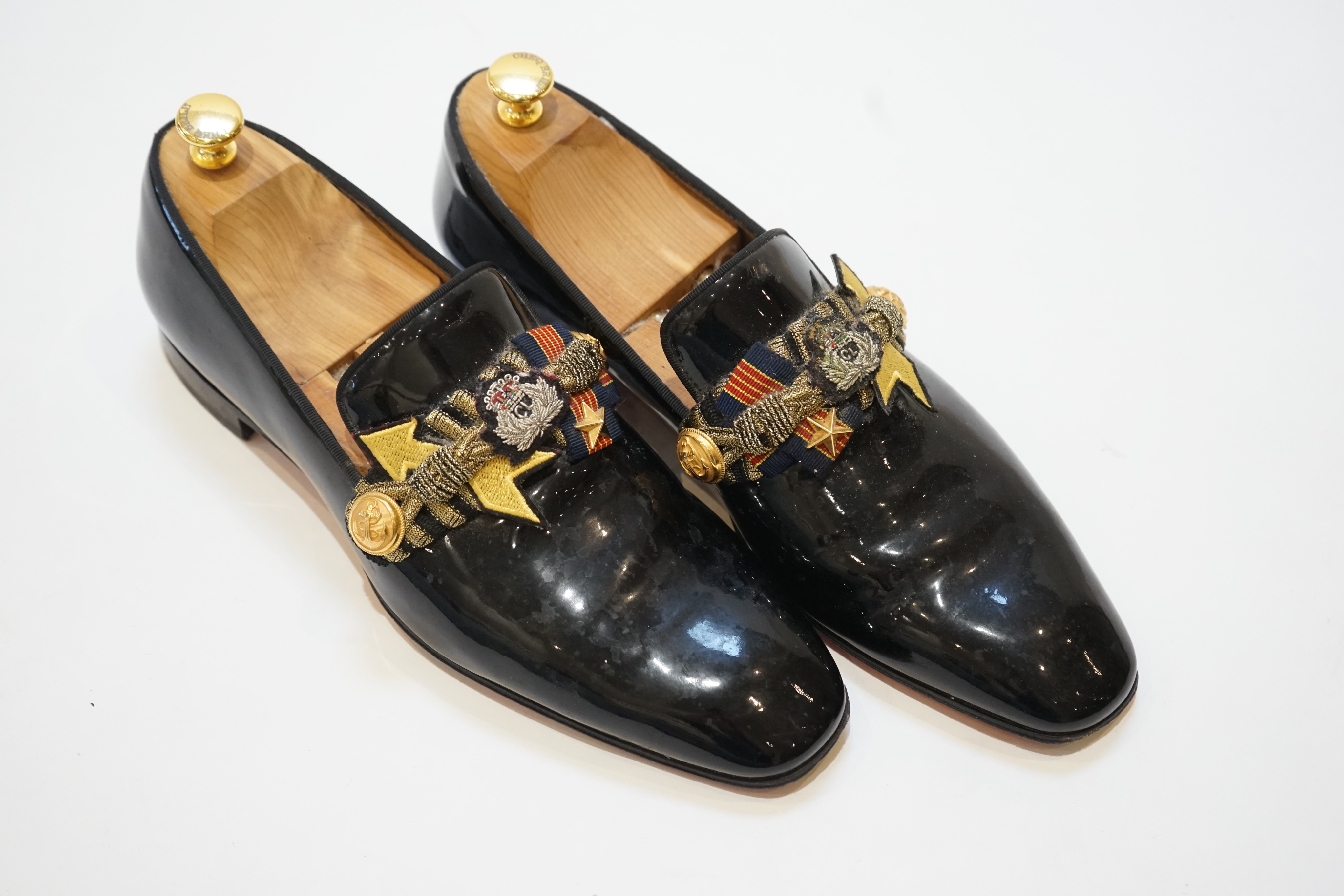 A pair of gentleman's Christian Louboutin patent leather dress shoes with applied and embroidered crests, size 43, in bag